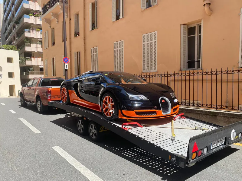 Schwarz-oranger Bugatti Veyron auf dem Transportanhänger