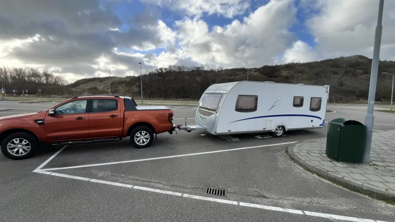Weißer Wohnwagen mit Zugfahrzeug bei einer Überführung