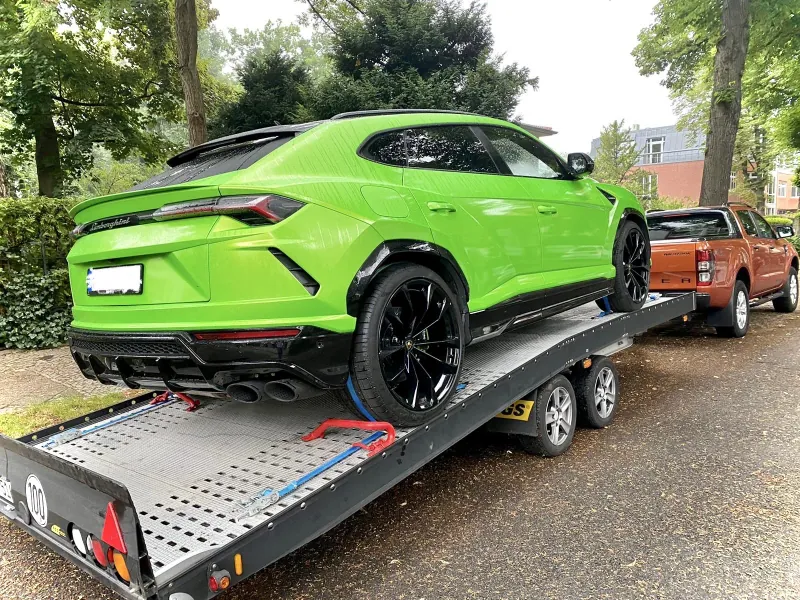 Grüner Lamborghini Urus auf einem Transportanhänger