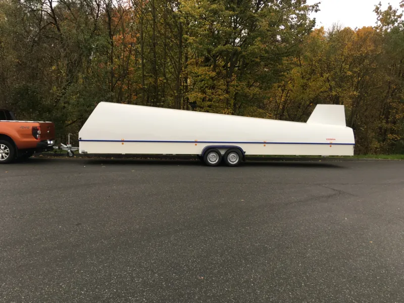 Langer weißer Segelflugzeuganhänger vor herbstlichem Wald