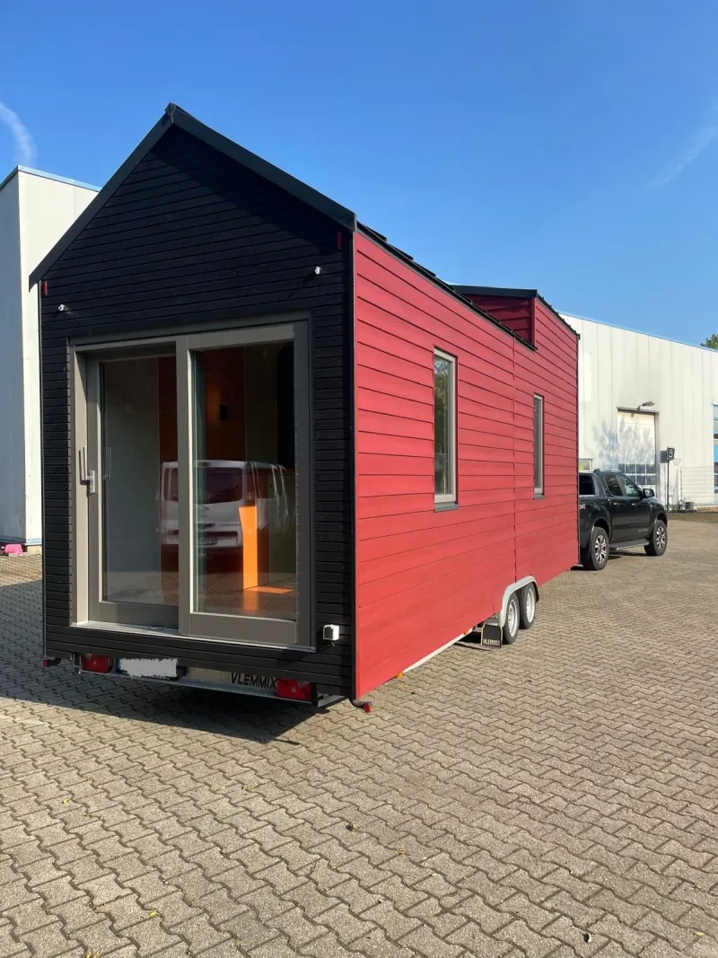 Rotes Tiny House auf einem Anhänger hinter einem Pickup